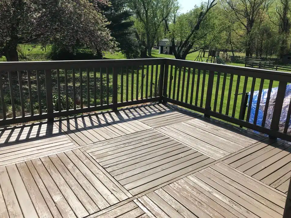 Restored wooden deck with a professional finish, surrounded by green grass and trees, showcasing the quality craftsmanship of Valentine Property Services.